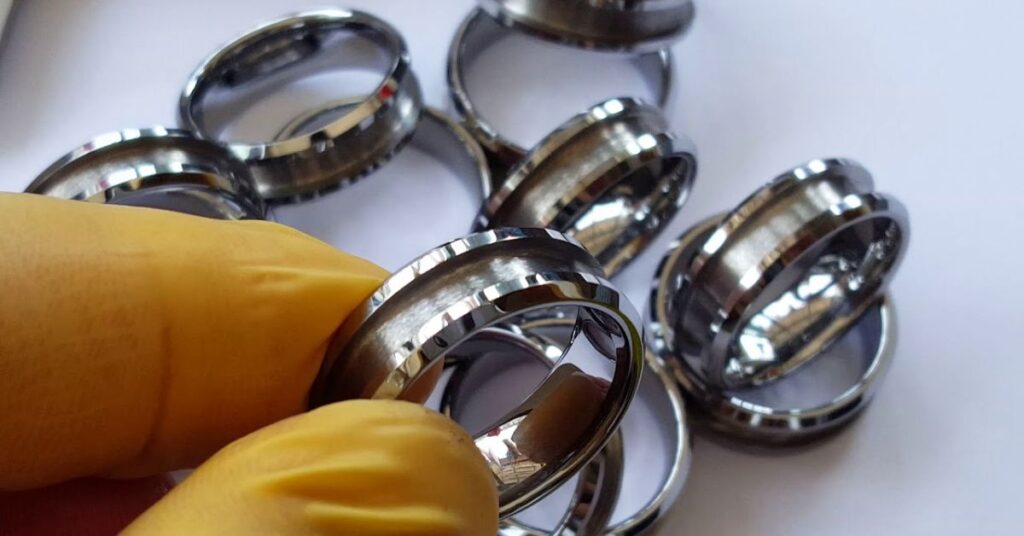 A person holds a black tungsten ring, showcasing its sleek design and potential for easy cleaning methods.