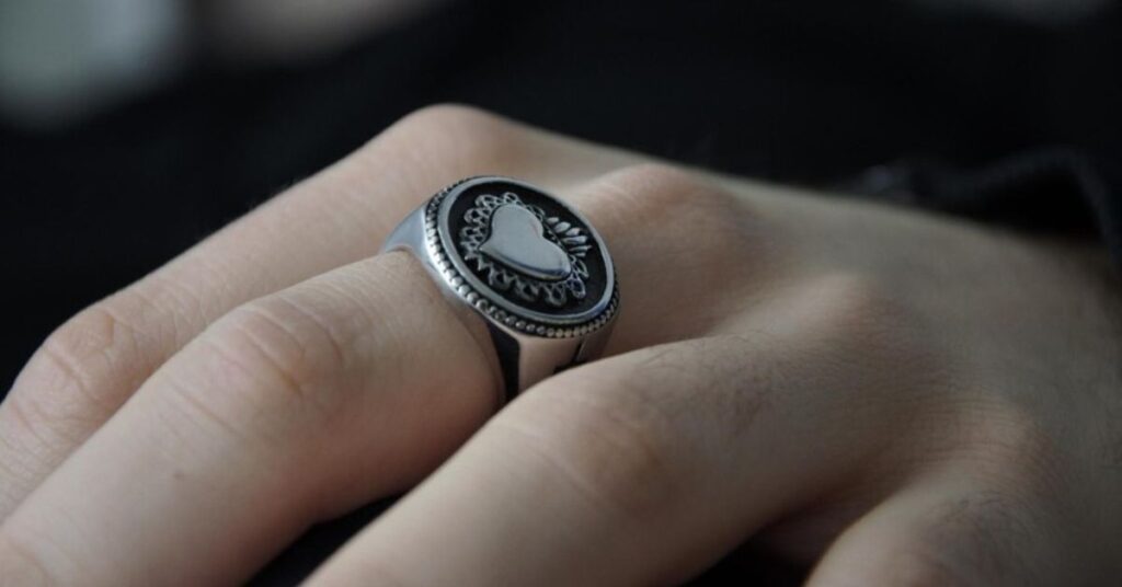 A person displays a signet ring featuring a striking black and white design, symbolizing heritage and authority.