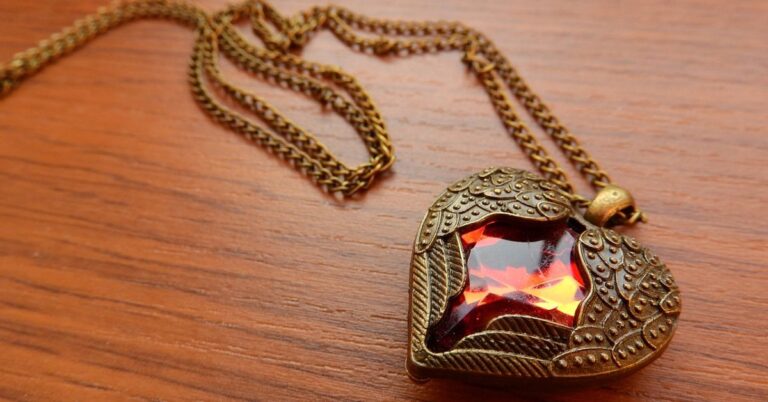 A red heart-shaped pendant on a gold chain, symbolizing love and elegance in jewelry design.