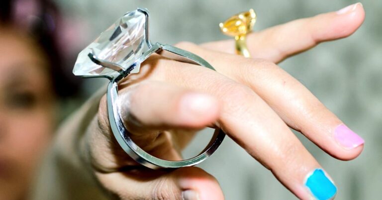 A woman holds a diamond ring, showcasing her own ring on her finger, symbolizing love and the art of ring resizing.