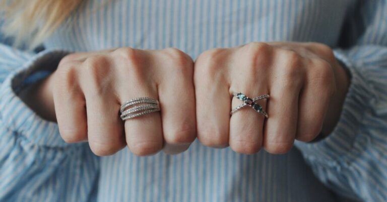 A woman showcases her hands adorned with two stylish rings, exemplifying chic stacking and balancing techniques for fashion.