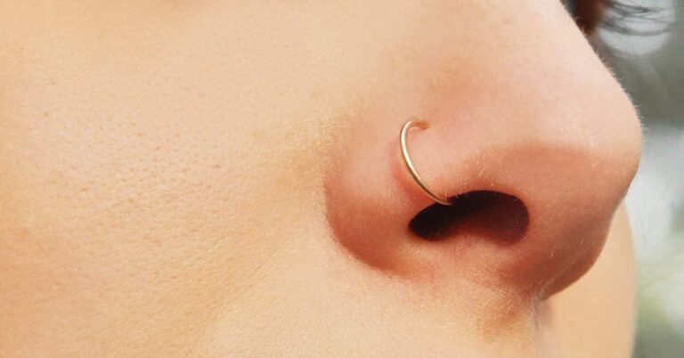 Close-up of a person showcasing a nose ring, emphasizing the importance of regular cleaning to prevent odors.