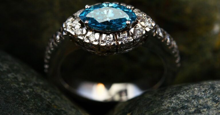 A blue diamond ring elegantly placed atop a collection of textured rocks, showcasing its brilliance and craftsmanship.